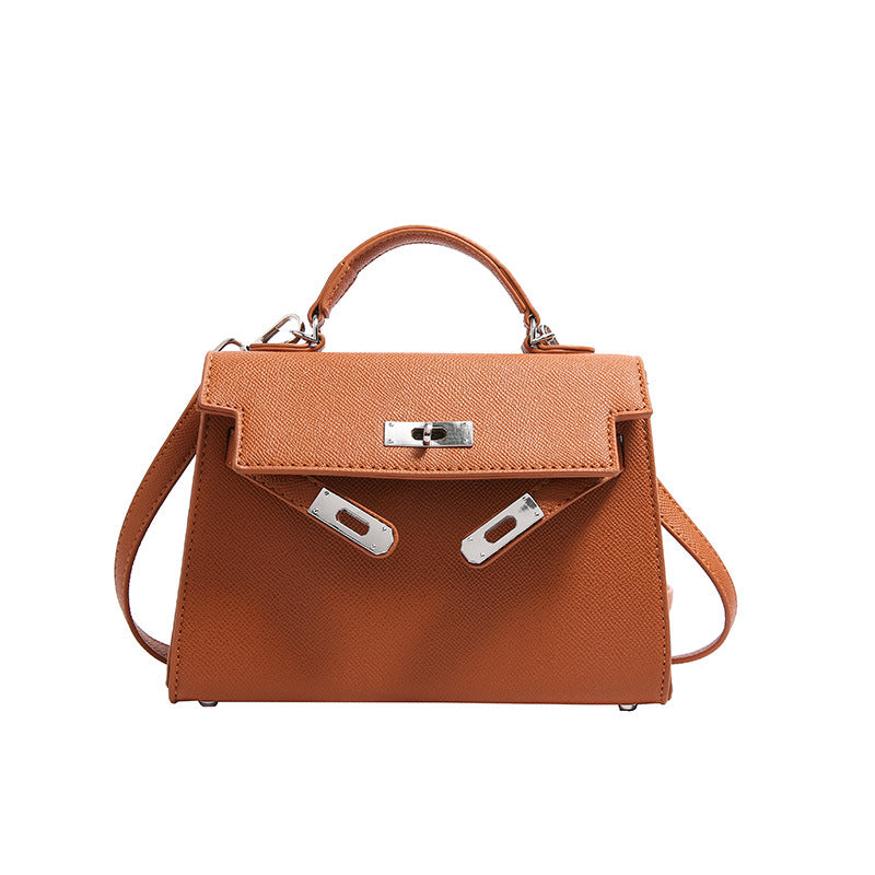 A woman carrying a small square bag with a lock